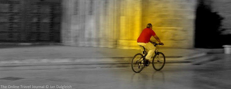Man cycling past the Seu at night, Valencia, Spain